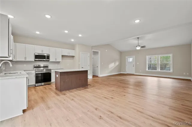 a kitchen with stainless steel appliances granite countertop a sink a stove a refrigerator and island with wooden floor