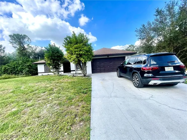 a car parked in front of white house with a small yard