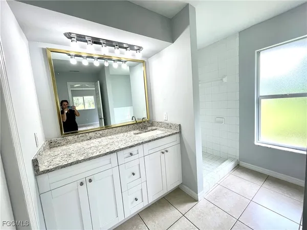 a bathroom with a granite countertop shower a sink and a mirror