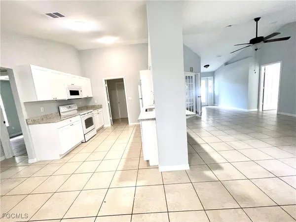 a view of a kitchen with kitchen island white cabinets and refrigerator