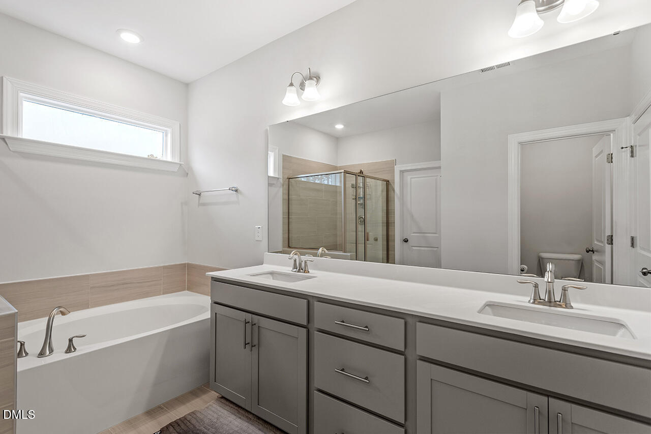3932 Mount Moran Road Raleigh, NC 27616 - Photo 24 of 40 a bathroom with a tub a sink double vanity and mirror