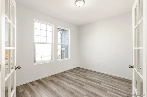 an empty room with wooden floor and windows