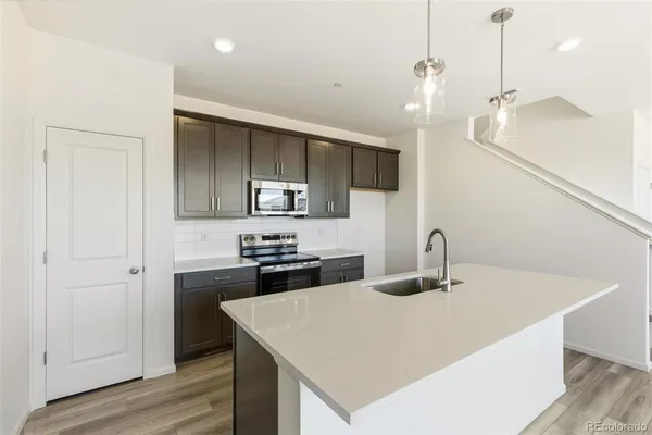 a kitchen with stainless steel appliances a sink stove and wooden floor