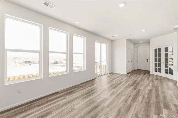 a view of an empty room with a window and wooden floor