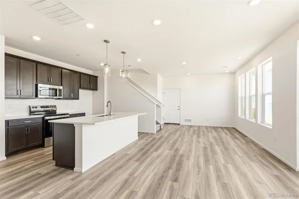 a large kitchen with stainless steel appliances kitchen island granite countertop a stove a sink dishwasher and a microwave oven with wooden floor