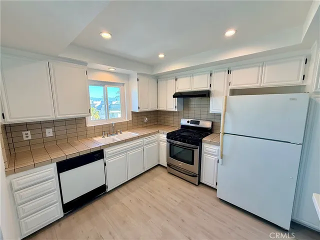 a kitchen with granite countertop white cabinets and white appliances