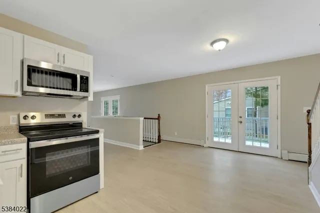 a kitchen with a refrigerator a stove top oven and white cabinets
