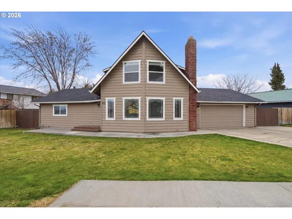a view of a yard in front of a house with a large tree