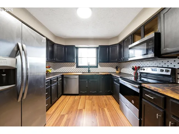 a kitchen with stainless steel appliances granite countertop a refrigerator a sink dishwasher a stove and a microwave oven on granite countertops