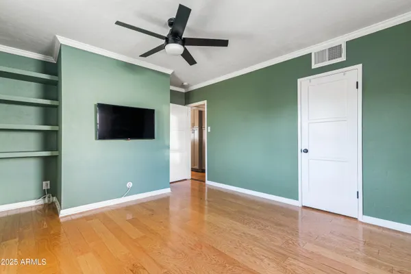 a view of empty room with wooden floor and fan