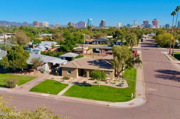 a view of a white house with a big yard plants and large trees