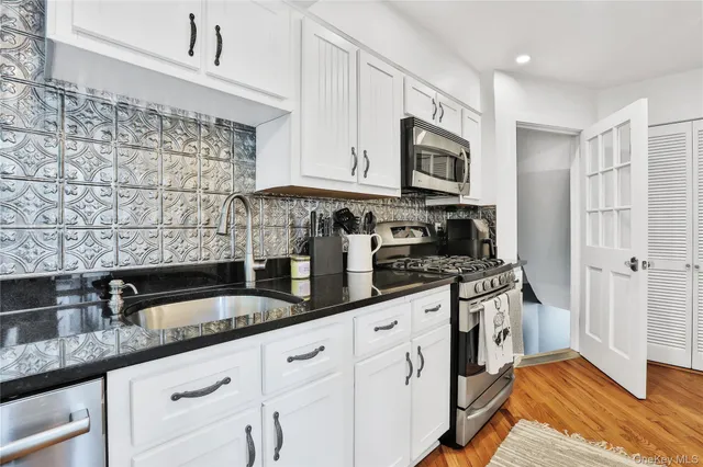 a kitchen with granite countertop a sink stainless steel appliances and cabinets