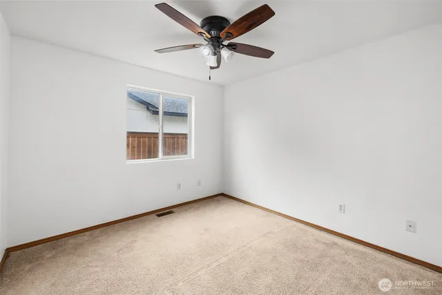 an empty room with a window and a fan