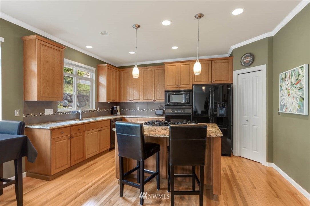 17112 164th Way Southeast Renton, WA 98058 - Photo 12 of 35 a kitchen with stainless steel appliances granite countertop a sink a stove a refrigerator cabinets and chairs