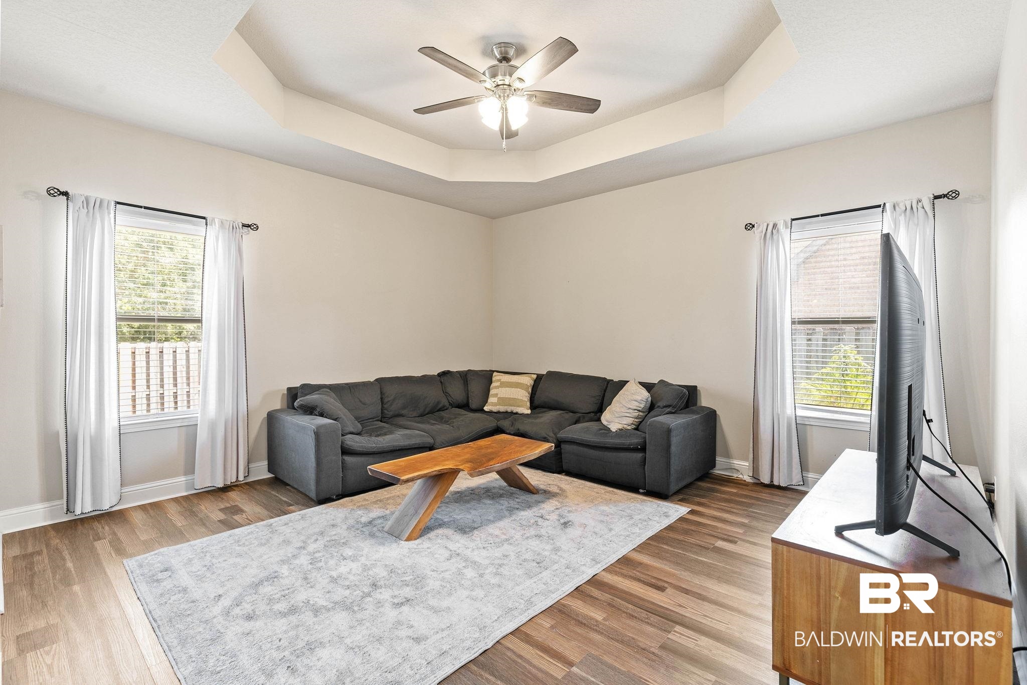 2216 Livingstone Court Mobile, AL 36695 - Photo 6 of 62 Living area featuring a tray ceiling, ceiling fan, and wood-finish flooring