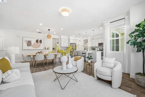 a living room with couches and kitchen view with wooden floor