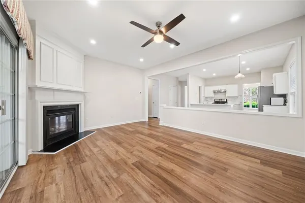 a view of an empty room with kitchen view and a fireplace