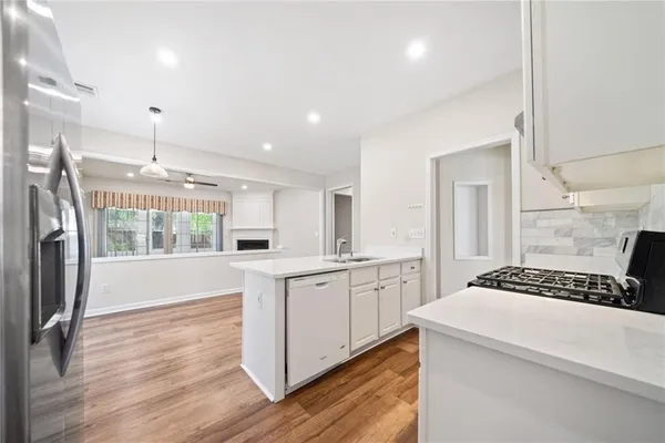 a kitchen with granite countertop a stove a sink dishwasher and a refrigerator with wooden floor