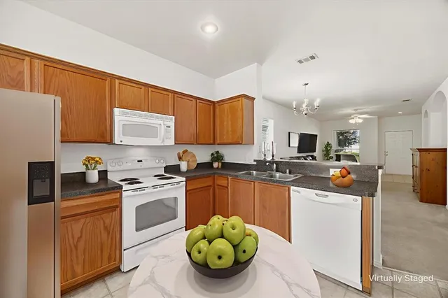 a kitchen with stainless steel appliances kitchen island granite countertop a sink dishwasher stove and refrigerator with wooden cabinets