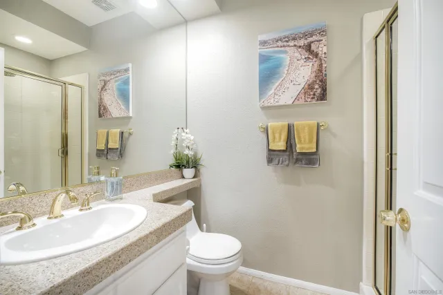 a bathroom with a granite countertop toilet a sink and a mirror