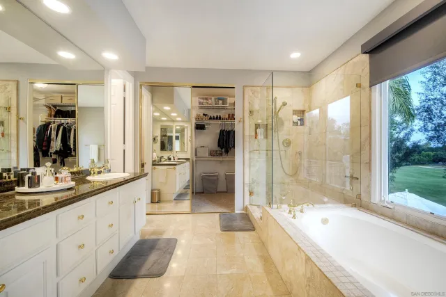 a bathroom with a double vanity sink and mirror with large tub