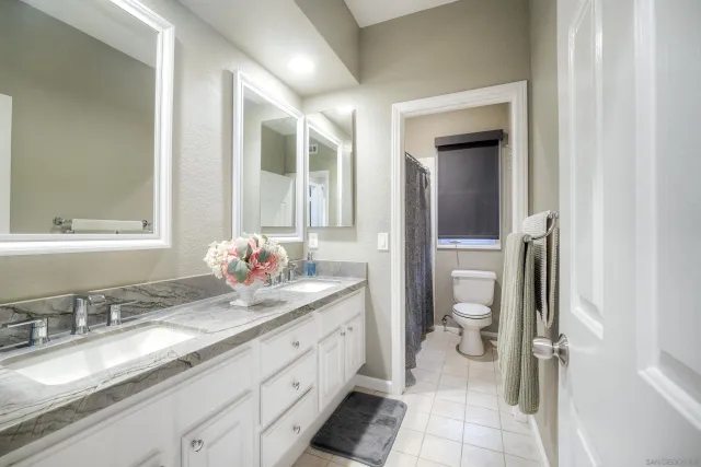 a bathroom with a granite countertop sink mirror and a toilet