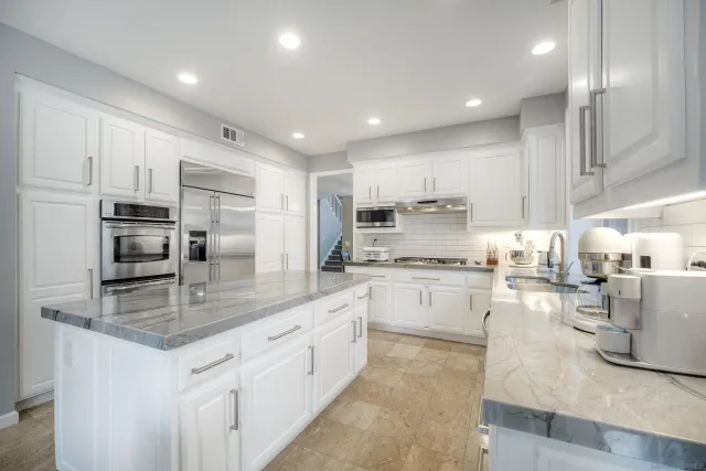 a kitchen with kitchen island granite countertop a sink counter top space appliances and cabinets