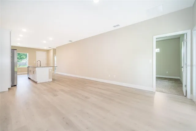 a view of a livingroom with wooden floor and a refrigerator