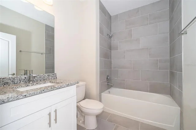 a bathroom with a granite countertop bathtub shower sink vanity mirror and toilet