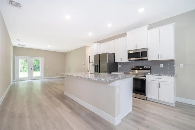 a kitchen with stainless steel appliances a stove top oven a sink a refrigerator a window