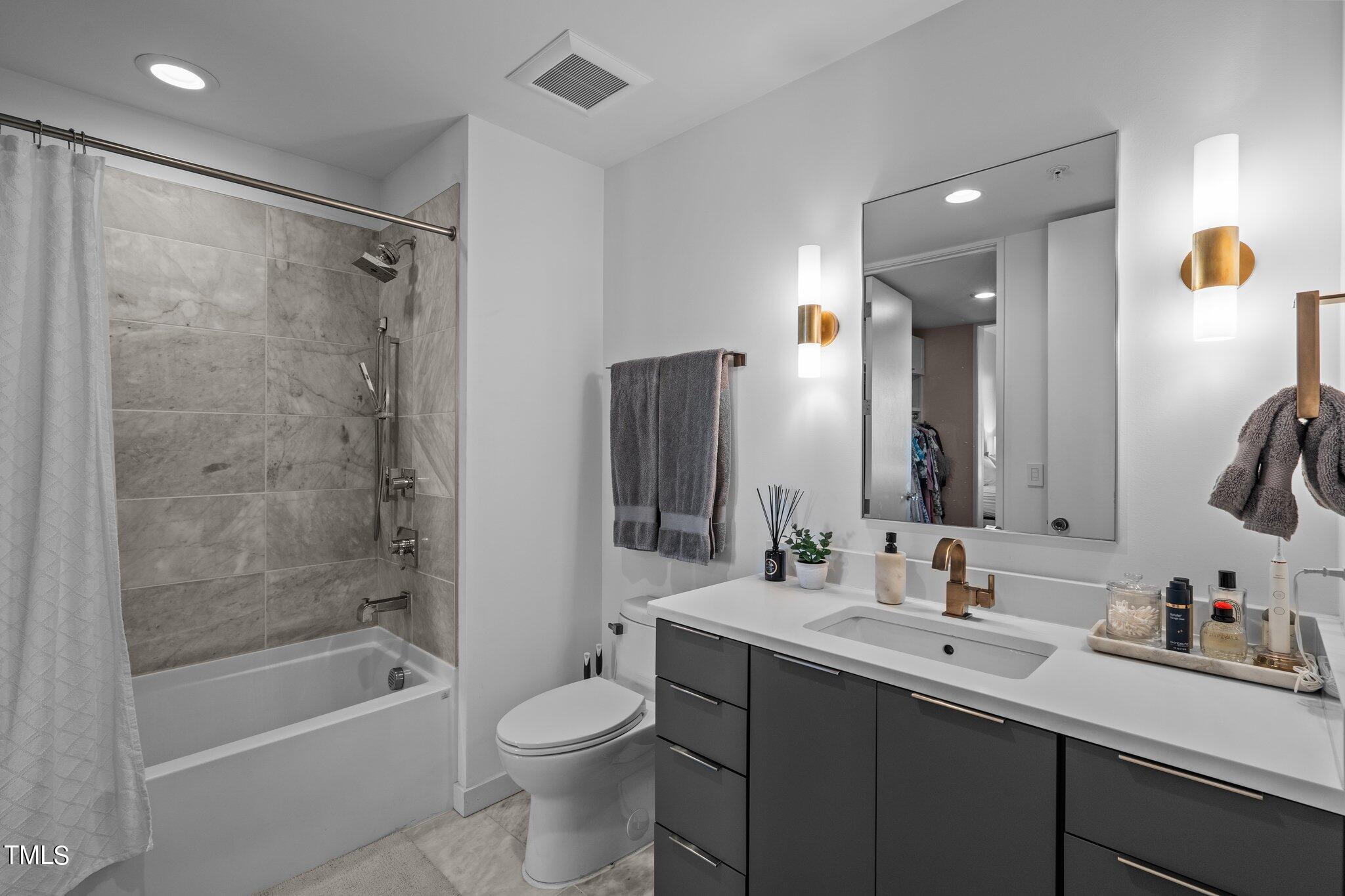 523 South West Street, Unit 304 Raleigh, NC 27601 - Photo 6 of 23 a bathroom with a bathtub shower sink vanity mirror and toilet