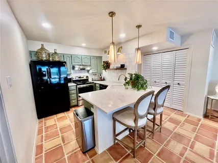 a kitchen with stainless steel appliances kitchen island granite countertop a refrigerator a stove a sink dishwasher with a dining table and chairs