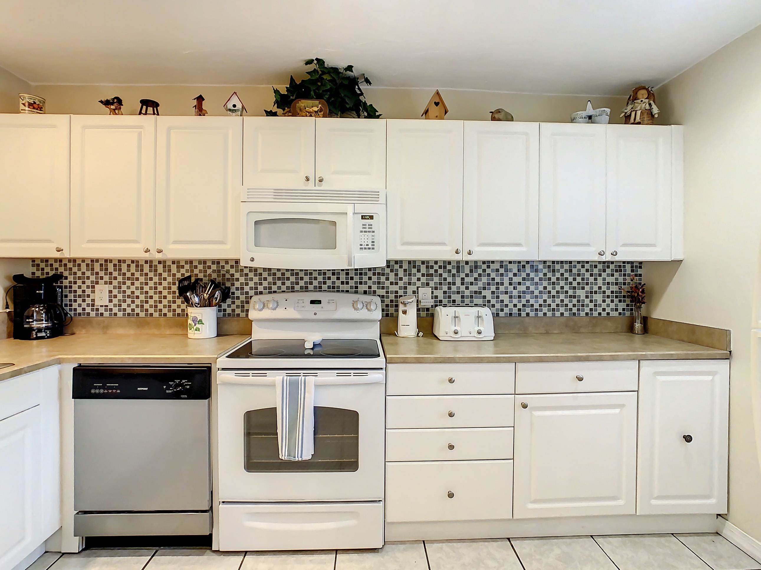 4 Ocean Trace Road, Unit 5 St. Augustine, FL 32080 - Photo 11 of 35 a kitchen with white cabinets and appliances