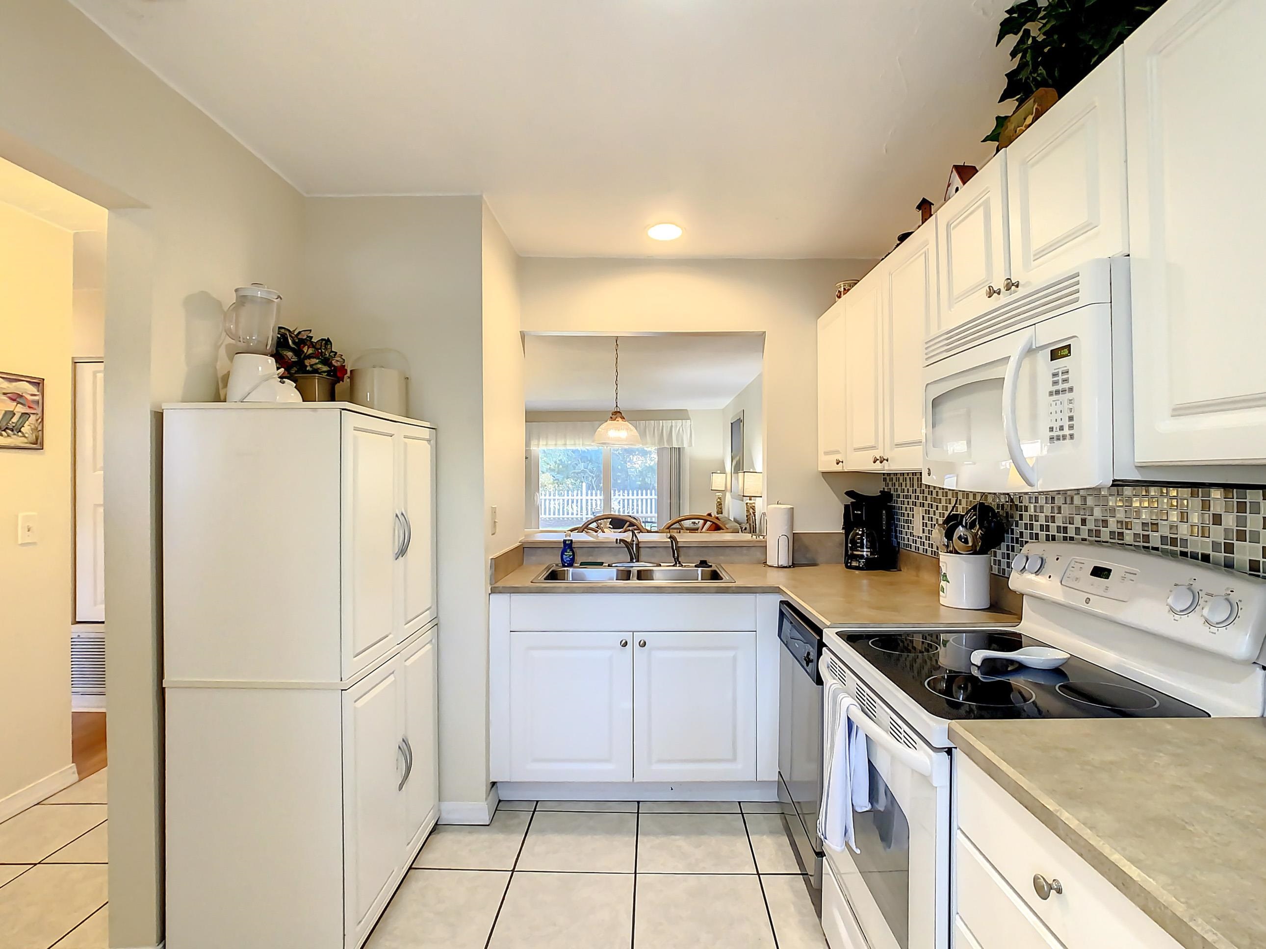 4 Ocean Trace Road, Unit 5 St. Augustine, FL 32080 - Photo 15 of 35 a kitchen with white cabinets and white appliances