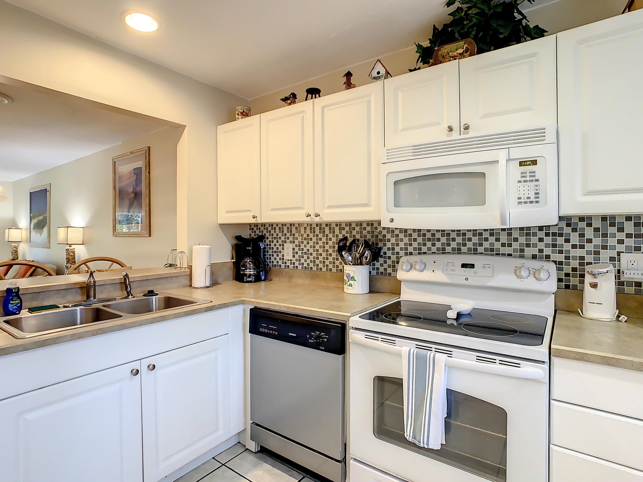 4 Ocean Trace Road, Unit 5 St. Augustine, FL 32080 - Photo 10 of 35 a kitchen with granite countertop white cabinets and white appliances