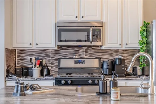 a kitchen with stainless steel appliances granite countertop a stove and white cabinets