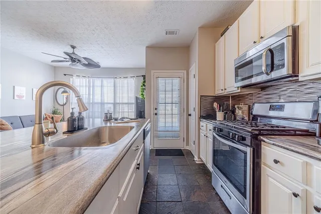 a kitchen with stainless steel appliances granite countertop a sink stove and cabinets