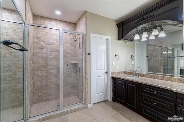 a bathroom with a granite countertop sink a mirror and shower