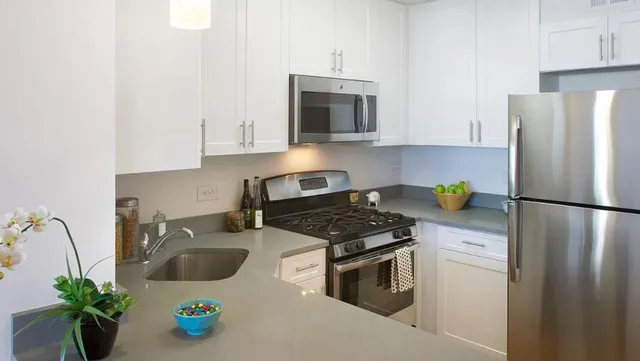 a kitchen with stainless steel appliances a stove a sink a refrigerator a microwave and cabinets