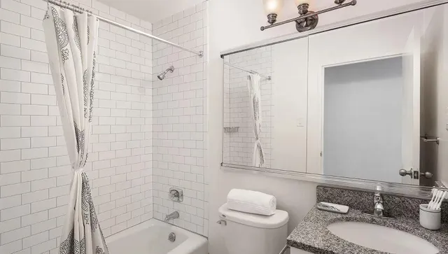 a bathroom with a granite countertop sink toilet a mirror and shower