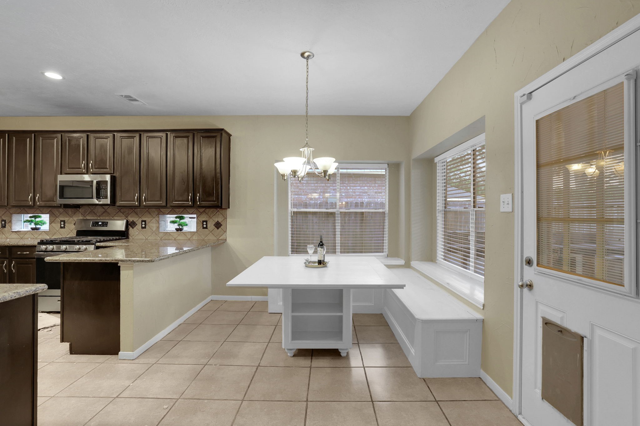 23207 Olive Ridge Court Katy, TX 77494 - Photo 12 of 46 a room with kitchen island granite countertop a sink dishwasher a stove a refrigerator and a dining table with wooden floor