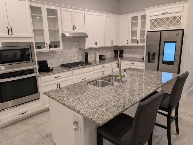 a kitchen with stainless steel appliances granite countertop a stove top oven a sink a dining table and chairs