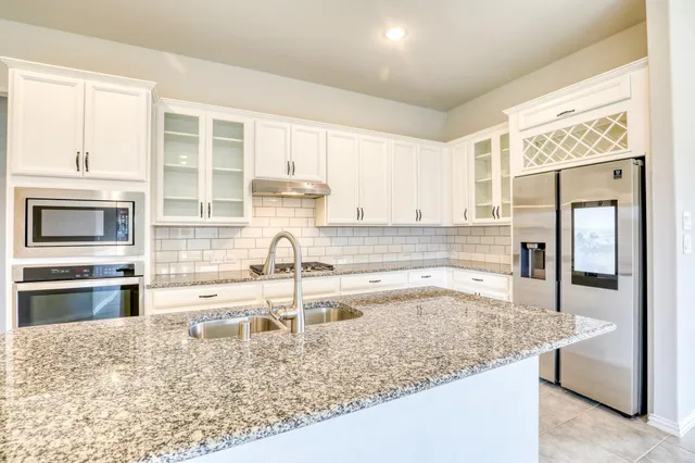 a kitchen with granite countertop a refrigerator and a stove top oven