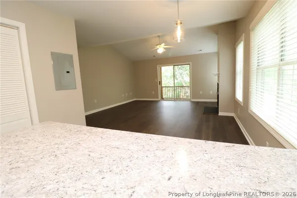 a view of an empty room with wooden floor and a window