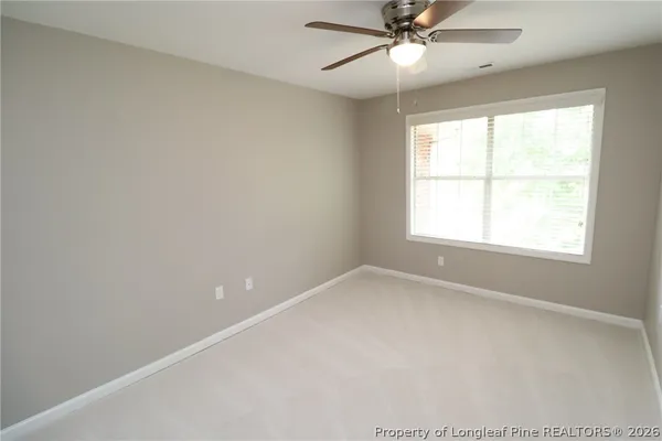 an empty room with a window and a fan