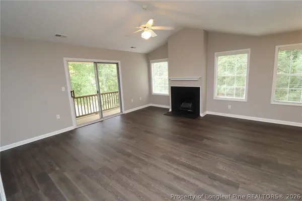 an empty room with windows fireplace and wooden floor