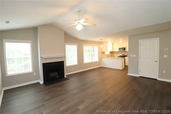 a view of a kitchen and an empty room with wooden floor and a window