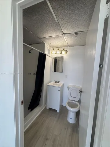 an empty room with wooden floor chandelier fan and windows