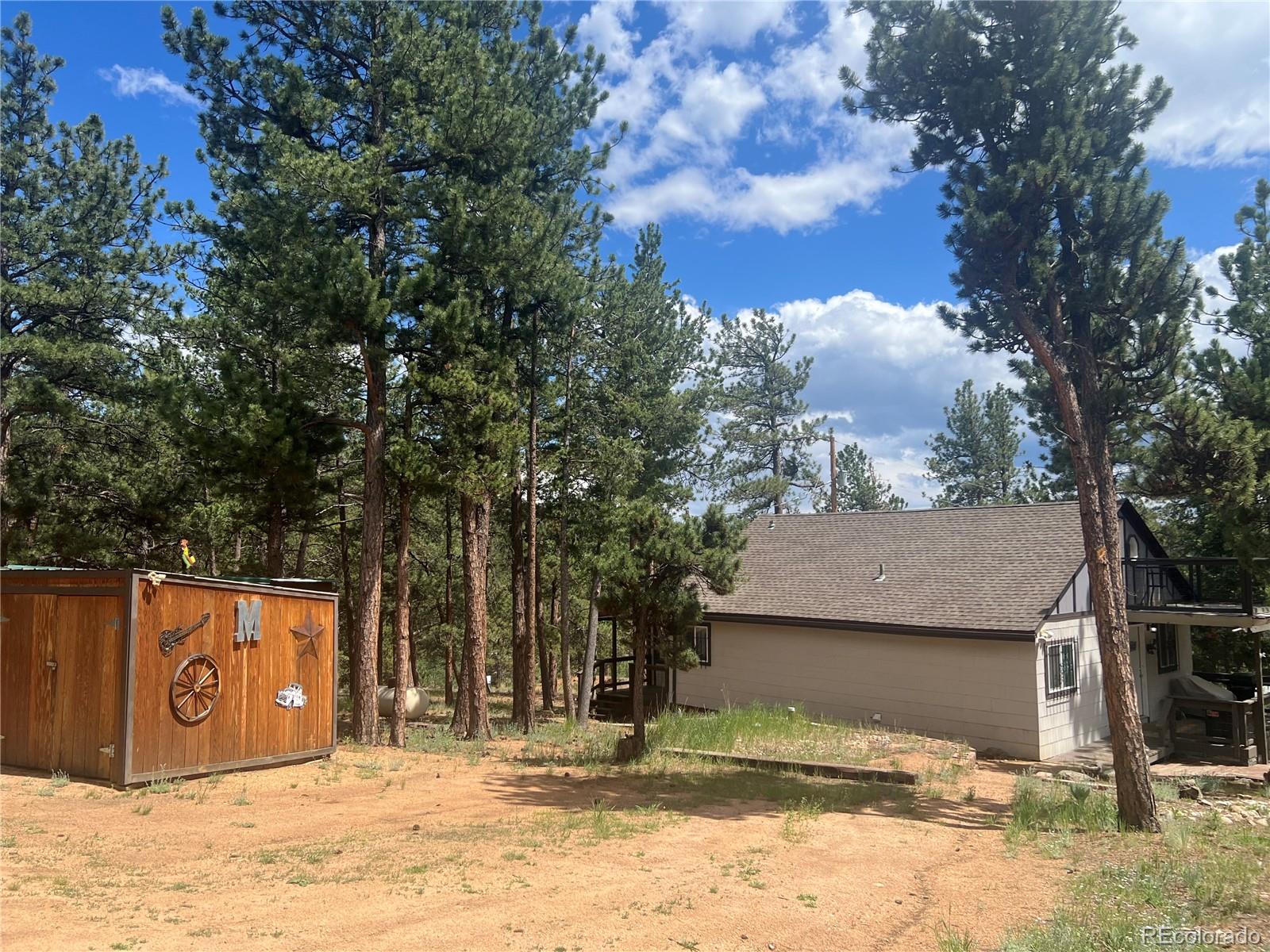 187 Johnson Road Bailey, CO 80421 - Photo 29 of 37 a street view with wooden fence and a large tree