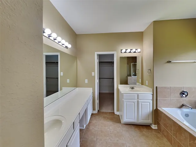a spacious bathroom with a tub sink and mirror